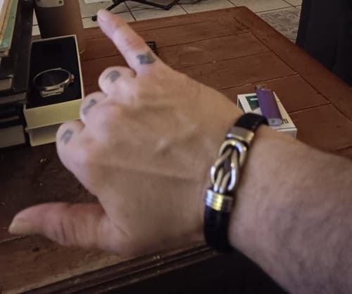 Close-up of a customer wearing a black leather bracelet with a silver knot-style clasp.