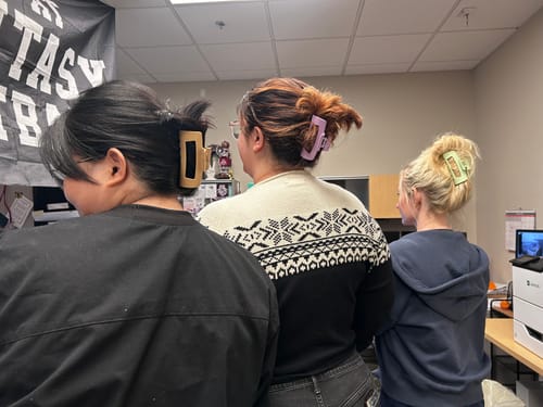 Customer's three workmates seen from behind, each wearing a different colored cloud clip in their hair.