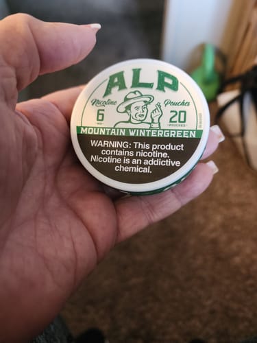 Customer holding a white and green tin of Mountain Wintergreen Nicotine Pouches.