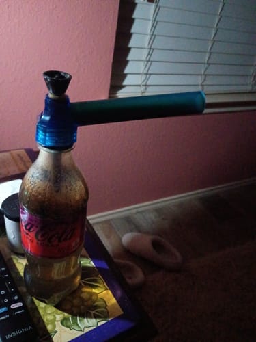 Reviewer's blue Top Puff Bong attached to a used Coca-Cola bottle, sitting on a table.