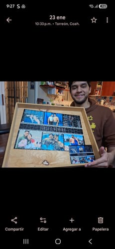 Cliente mostrando su Rompecabezas Collage 2 terminado dentro de un marco de madera clara.