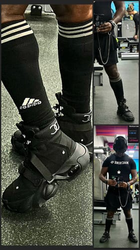Reviewer at the gym wearing the black, high-top Dual-Strap Stealth Runner Boots with shorts and knee-high socks.