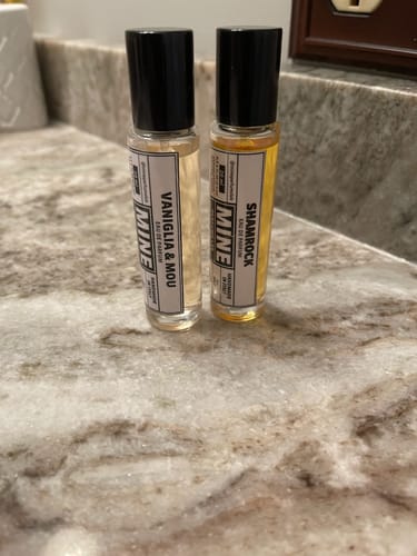 Recensore mostra il suo profumo VANIGLIA & MOU accanto a un altro flacone su un bancone.