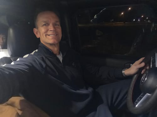 Customer smiling while sitting in a car at night, wearing the velour top mentioned in the review.