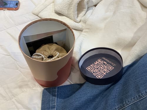 Empaque del cliente para el Rompecabezas Personalizable, mostrando una caja cilíndrica abierta y una bolsa adentro.