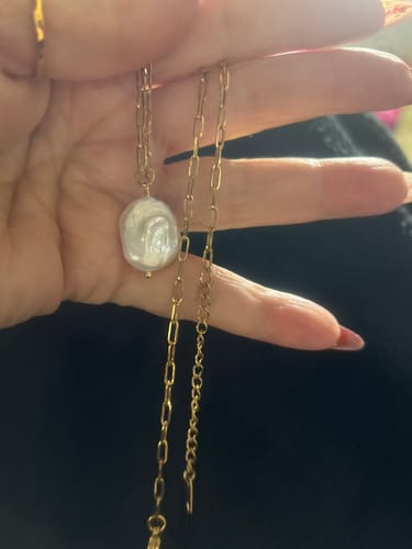 Reviewer's hand holding the gold Hanalei Pearl Coin Paperclip Necklace, showing the pearl pendant and extender chain.
