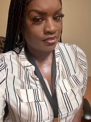 Reviewer selfie showing the black HD Knotless Braid Wig, with braids styled over one shoulder.