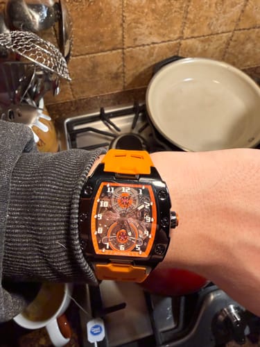 Customer's close-up of the Lucky Fours® Polaris watch on their wrist, showing the orange band and black case.