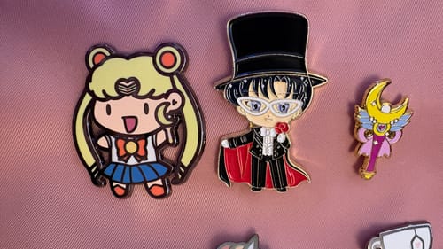 Customer's Serena Pin displayed on pink fabric next to a Tuxedo Mask pin and a wand pin.