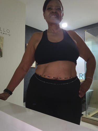 A reviewer shows off the 'Black is Beautiful' clasp waist beads worn around their waist with a black top.