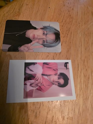 Customer's two photocards included with the STRAY KIDS album displayed on a wooden surface.
