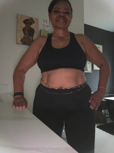 Customer wearing multiple strands of Opulence Clasp Waist Beads around their waist with a black athletic top.