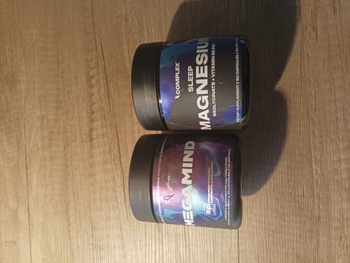 Reviewer's two black tubs of Complex Sleep Magnesium and Megamind supplements on a wooden surface.