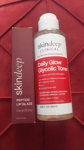 Reviewer's box for the skindeep Peptide Lip Glaze in Deep Berry, pictured next to a bottle of Daily Glow Glycolic Toner.