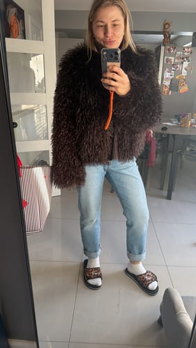Reviewer takes a mirror selfie wearing the shaggy brown Bella Faux Fur Coat with jeans.