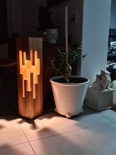Die beleuchtete STALAKTIT Holzsäule eines Kunden steht in einem dunklen Raum und wirft Schatten auf den Boden.