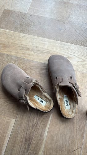 Customer's pair of light brown OLIVIER FUR clogs, showing the soft suede and warm shearling lining on a wood floor.