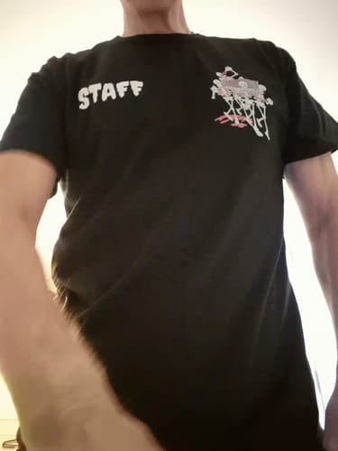 Reviewer wearing the custom black unisex t-shirt with 'STAFF' and a graphic printed on the chest.
