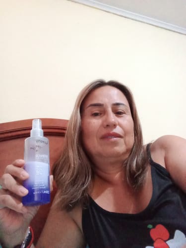 Una clienta sostiene la botella del Spray Bifásico 10 en 1 en su mano.