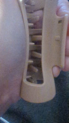 Close-up of a customer holding a beige cloud clip in their hand, showing the inner teeth.