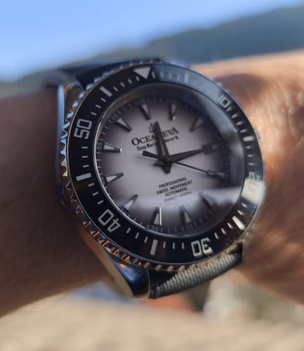 Customer's close-up of the Oceaneva Deep Marine Explorer watch on their wrist, showing the white burst dial and black bezel.