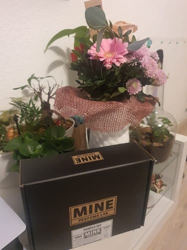 Recensore mostra la scatola nera del Set campioni dolci e calde accanto a un mazzo di fiori.