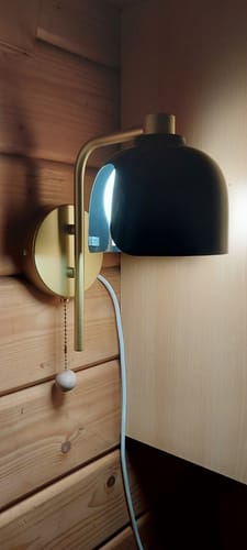 Rezensent zeigt eine Seitenansicht der modifizierten, leuchtenden OSRAM DECOR Corolle Wandleuchte an einer Holzwand.