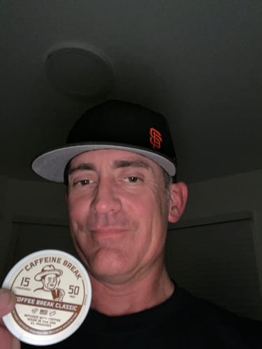 Customer holding up a round tin of Coffee Break Caffeine Pouches.