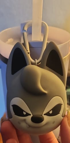 Customer holding the grey, wolf-like character cover of the SKZOO speaker, with its clip attached.