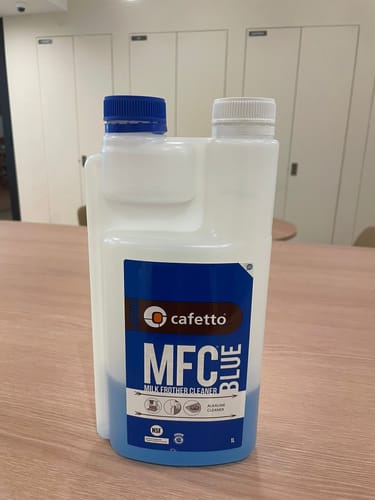 Customer's Cafetto MFC Blue Milk Frother Cleaner in its distinctive bottle on a wooden table.