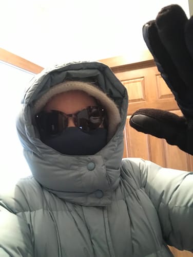 Reviewer bundled for cold weather, wearing the steel blue Neck Gaiter pulled over their mouth and nose with a winter coat.