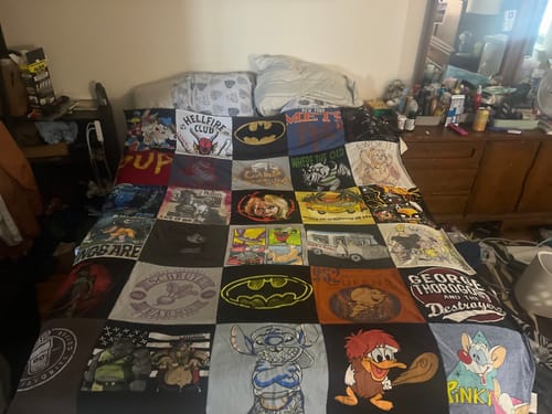 Customer's full-size Premium T-Shirt Quilt made from various graphic tees, spread across a bed in a bedroom.