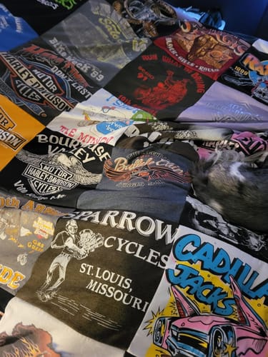 Customer's Premium T Shirt Quilt spread on a bed, showing various event and motorcycle-themed patches from saved t-shirts.