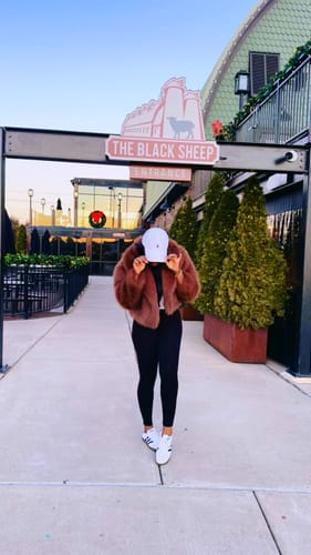 Reviewer showing a full-body view of the black NW Sculpt Leggings styled with a brown jacket and white sneakers outdoors.