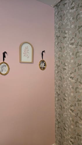 Reviewer's Finlay Wallpaper used as an accent wall next to a solid pink wall with framed art.