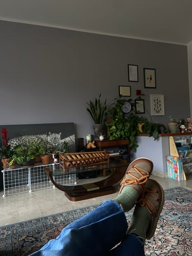 Customer relaxing with their feet up, showing the green LINDSAY mules with tan laces and green socks.