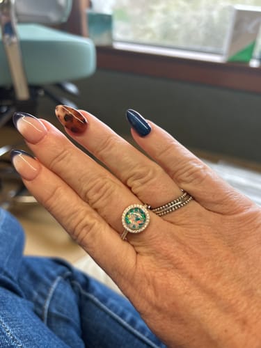 A reviewer's hand wearing the Bedazzled Circle Opal Cremation Ring with a lovely green opal center.