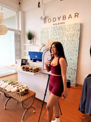 Customer smiling in the black-cherry Essentials Short and matching top at her birthday pilates event.