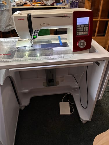 Customer's white Koala Quilter's Vision cabinet with a sewing machine positioned in the hydraulic lift, flush with the top surface.
