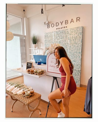 Reviewer laughing while wearing the black-cherry Essentials Short and matching top in a pilates studio.