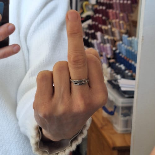 Close-up of a reviewer's hand wearing the silver 'I F♡cking Love You Ring' on an extended middle finger.