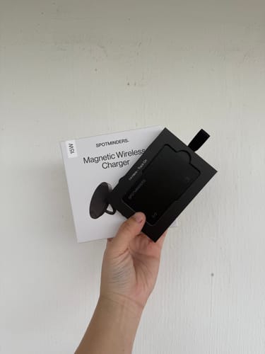Reviewer's hand holding the SPOTMINDERS Tracking Card in its black packaging, with another product box in the background.