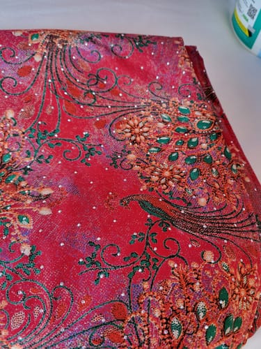 Customer's close-up of the red Diamante Printed Viscose, featuring a detailed peacock pattern with sparkly dots.