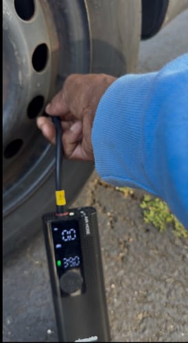 Customer using the portable Airmoto to inflate a vehicle tire, with the digital display on.