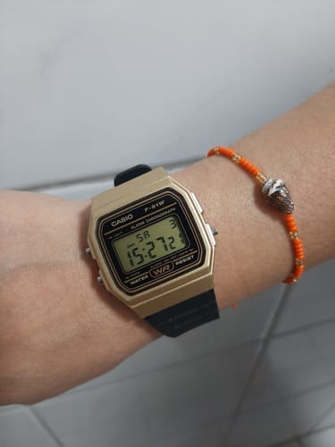 Cliente mostrando su reloj Casio Vintage dorado con correa negra en la muñeca.