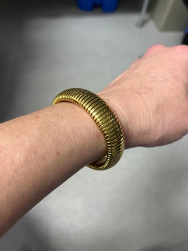 A reviewer's wrist wearing the gold-colored, ribbed Ibiza Chunky Bangle.