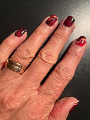 Kundin zeigt ihre Nägel mit den schönen, roten 'Sienna Marble' Nagelfolien.