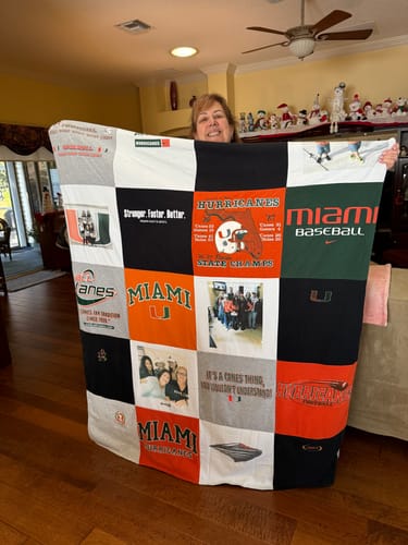 Customer holding up their custom Premium T Shirt Quilt made from colorful Miami Hurricanes shirts and photos.
