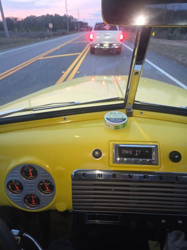 Customer's can of Spearmint Nicotine Pouches on the dashboard of a vintage yellow car.