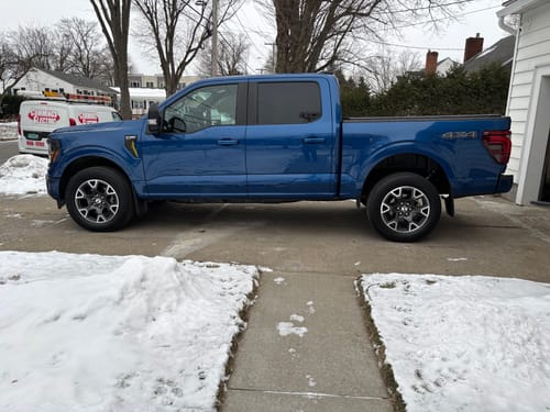 Customer's blue Ford F-150 truck with the SD Kit installed, viewed from the side while parked in a snowy driveway.